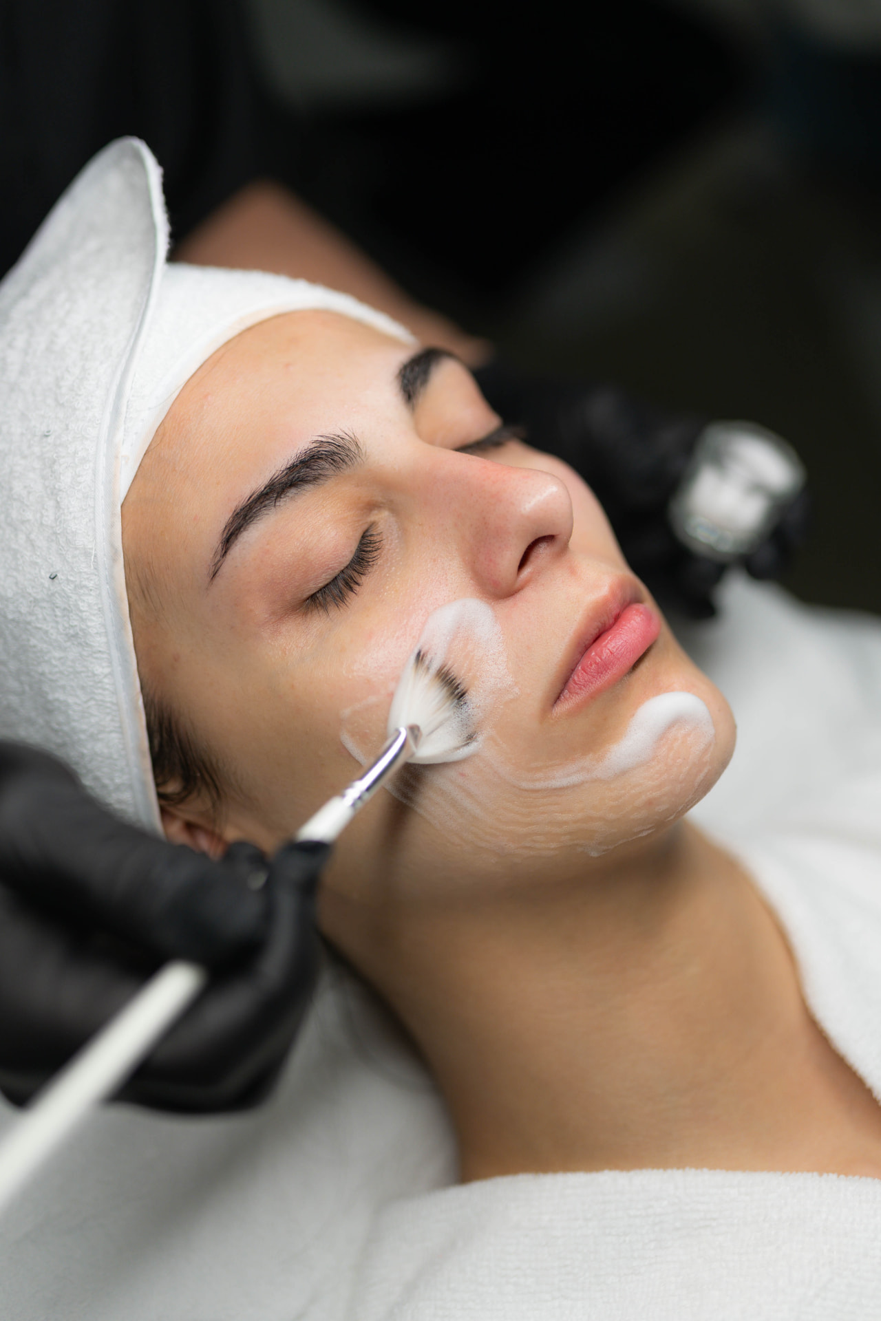 Tratamiento facial con pincel aplicando mascarilla sobre la piel